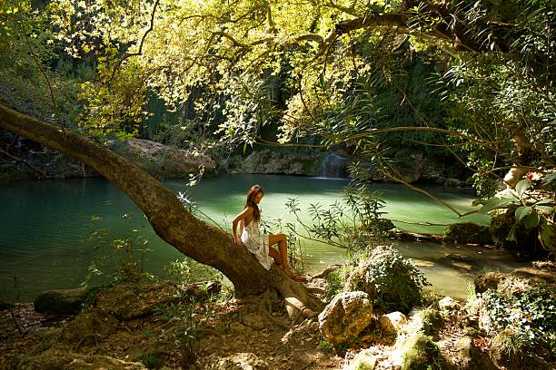 istock Woman Relaxing by a Forest Waterfall Pool 2203938481