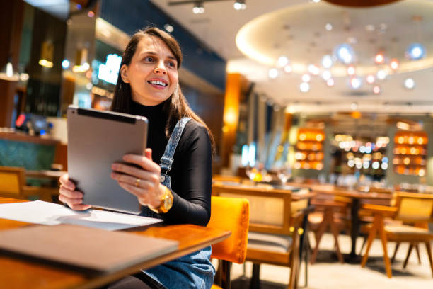 istock Smiling brunette in a coffee shop with her IPad 2203939952