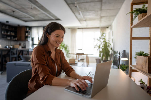 istock Young woman working from home on laptop and smiling 2203940853