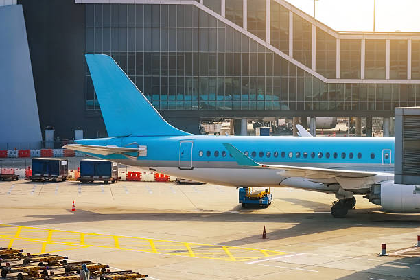 istock Blue airplane jet connected to terminal via jet bridge 2203941553