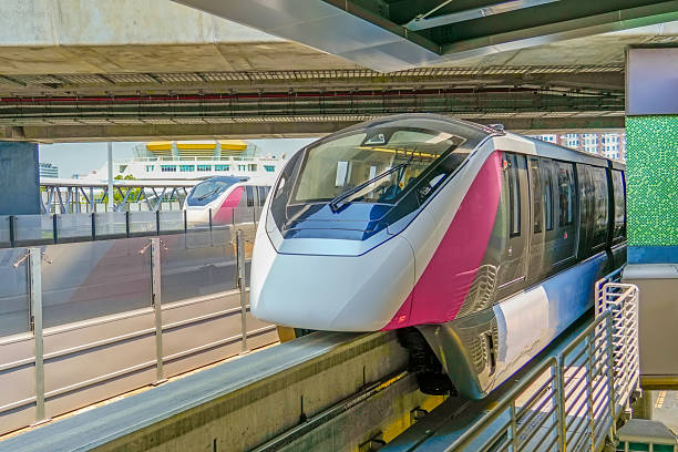 Modern high-speed monorail trains run parallel through the station under the road interchange bridge