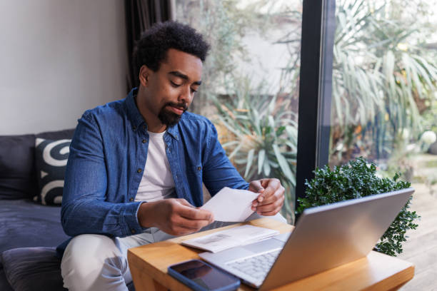 istock Man reviewing financial documents at home using a laptop and smartphone 2203942974