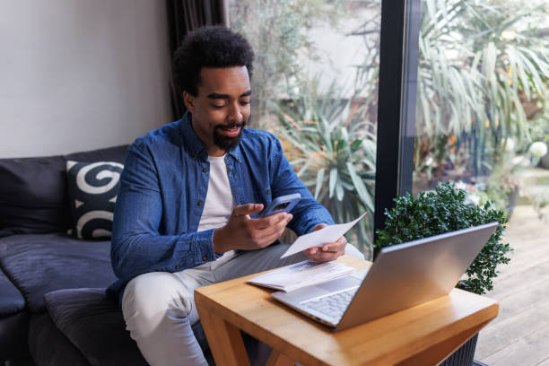 istock Man using phone and laptop for online banking or bill payment at home 2203942975