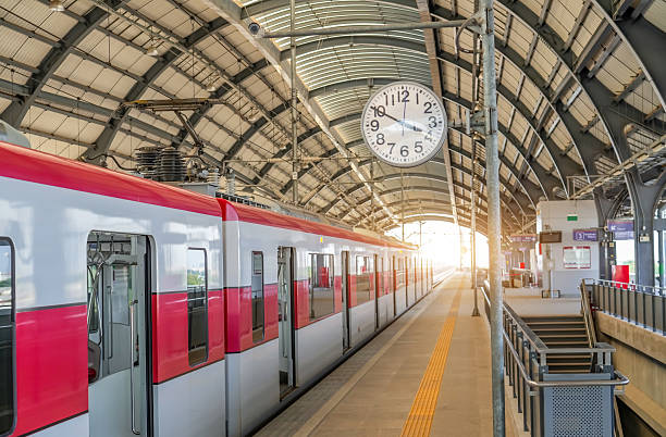 istock Clock on a pole on the passenger platform at a train station awaiting the departure of commuter electric train waiting for passengers with doors open. 2203943478