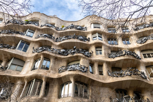 Casa Milàs undulating facade with ornate balconies Barcelona, Catalonia - Spain - 01-08-2025: Close-up of Casa Milàs wavy stone facade with intricate wrought iron balconies, organic shapes, and windows under a partly cloudy sky. casa mil�� stock pictures, royalty-free photos & images