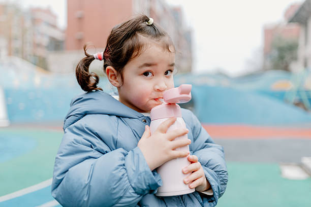 istock Chinese girl drinking water from her pink bottle 2203946565