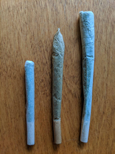 istock Three Rolled Paper Joints of Different Sizes on Wooden Surface 2203948263