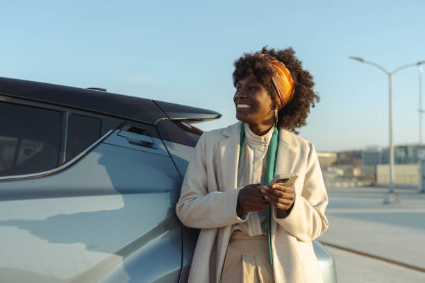 istock Woman leaning on a car using her smartphone in a modern outdoor setting 2203950322