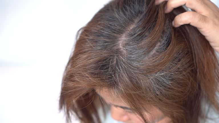 Woman checking thinning hair, hair Loss, damaged strands, and grey roots due to chemical treatments or dyes
