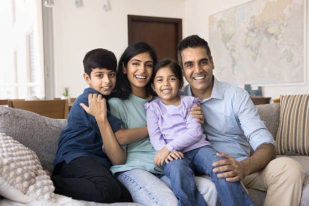 istock Indian couple and kids relaxing on couch posing for camera 2203955404