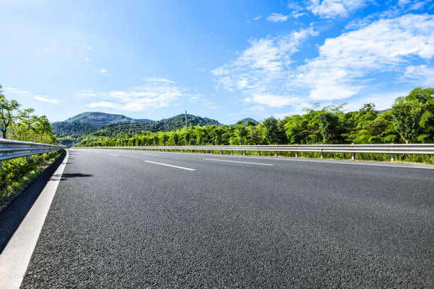 Empty asphalt road with mountain and green trees in summer landscape
