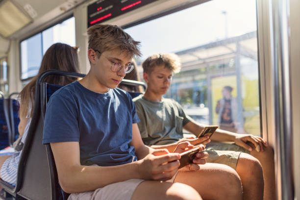 istock Two teenage boys using phones in a modern tramway. 2203961245
