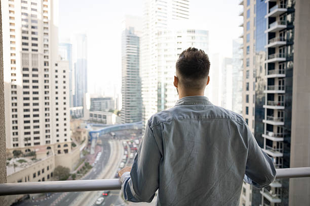 Man standing on balcony and gazing out at big city