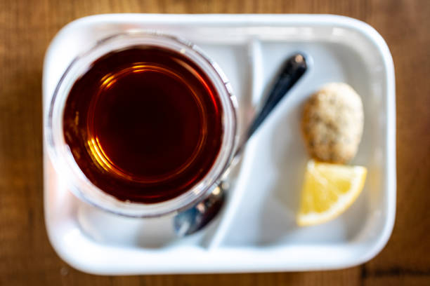 A close-up shot of aromatic Turkish black tea served in traditional glass cups, accompanied by a cookie and a fresh lemon slice. Set in a modern, fresh home interior, this warm and inviting morning scene captures the essence of relaxation and cultural tradition. Perfect for themes of breakfast, hospitality, and cozy living.