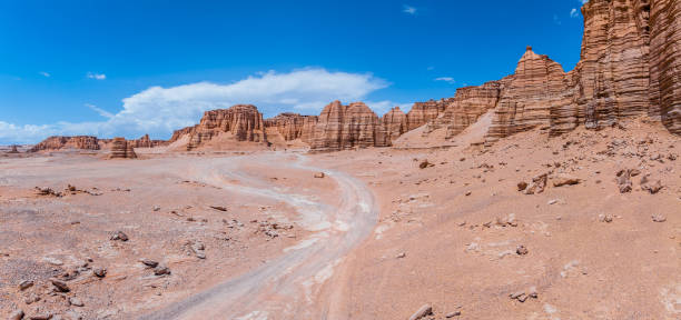 istock The road leads through the desolate yardang landform landscape under blue sky 2203968195
