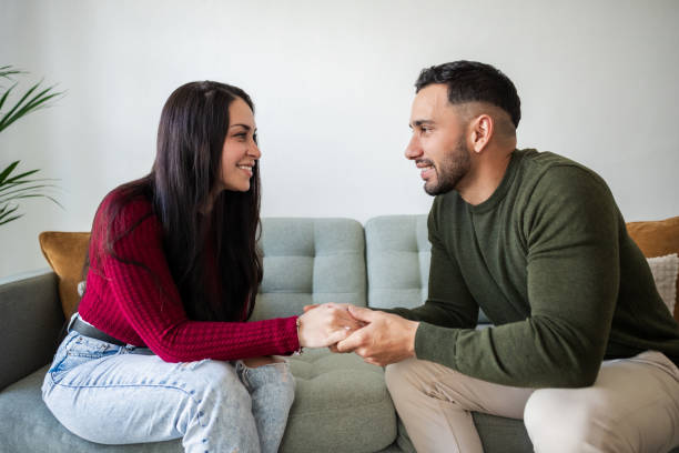 istock Young couple holding hands and talking on sofa at home 2203976556