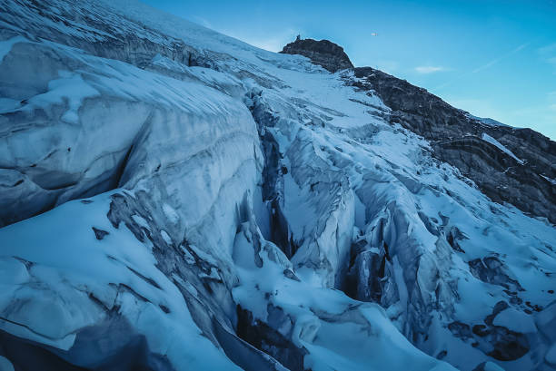 View up glacier and crevasses to mountain peak in moody light, Valais, Swiss Alps