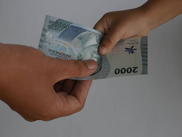 istock hand receiving a 2,000 rupiah bill 2203982483