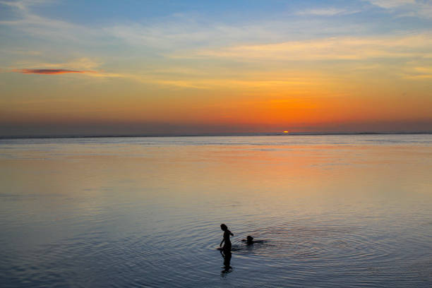 A couple is enjoying a sunset while in the water at Bora Bora.