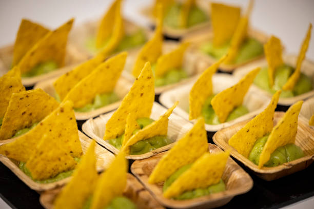 Elegant individual servings of crispy nacho chips with smooth, fresh guacamole, beautifully arranged for a stylish catering experience. A perfect appetizer for events, cocktail parties, and upscale gatherings