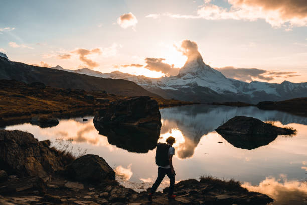 istock Hiker explores alpine lake below snowcapped mountain at sunrise 2203987272