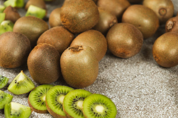 istock Fresh kiwi fruit, whole and sliced kiwi on a stone gray table 2203987376