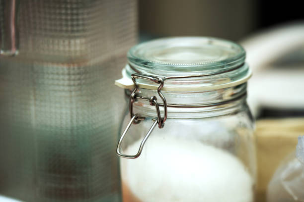 metal swing latch lock securing a glass jar filled with sugar. The lock adds a rustic touch to the kitchen storage, enhancing the jar's aesthetic appeal