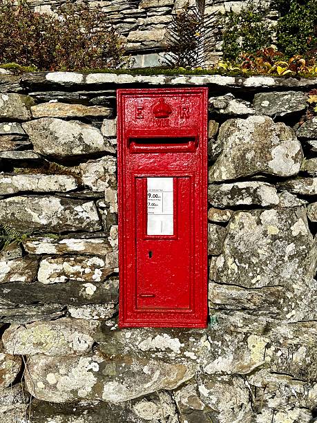 istock Vibrant English red post box set into a rustic stone wall 2203993286