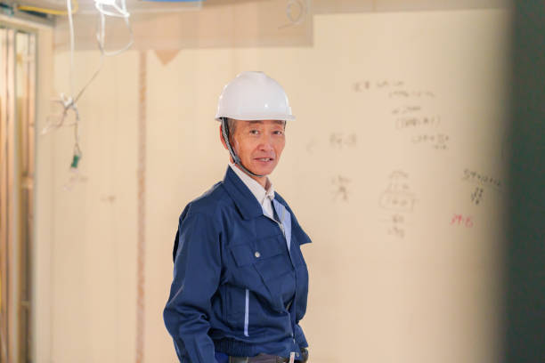 Manual workers cooperating while carrying wood plank at construction site. Blurred motion. Copy space.