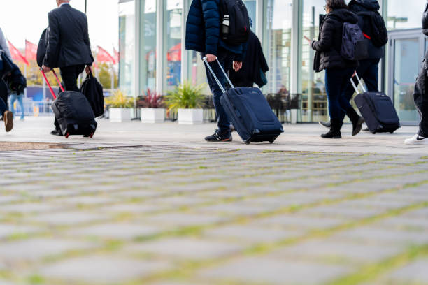 Barcelona, Spain. 03/06/2025. Mobile World Congress (MWC) held at the Fira of Barcelona. Professional colleagues walking, rolling wheeled suitcases through corporate environment
