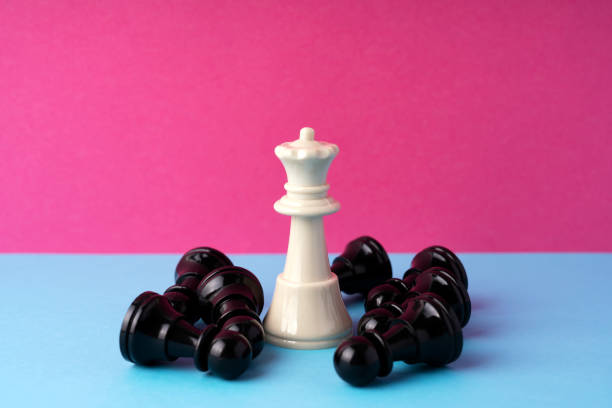 Chess piece of queen and the fallen pawn pink background