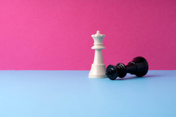 istock Black king checkmate by a queen piece on pink and blue background 2204001364