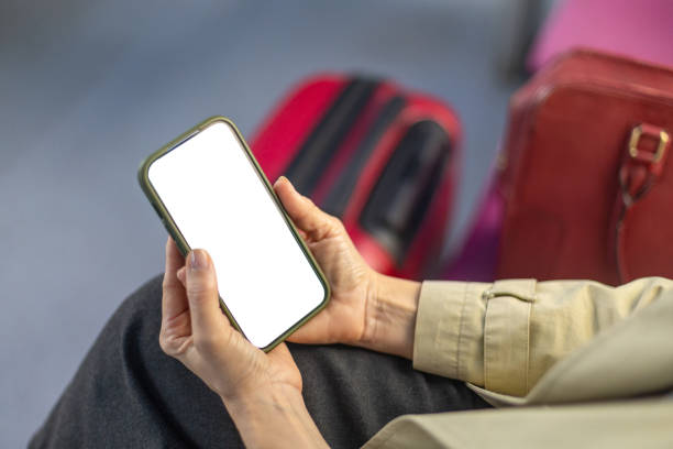 istock Businesswoman using smartphone while waiting at airport with luggage 2204002131
