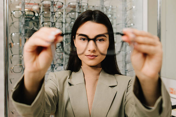 istock Customer chooses eyeglasses with clear lenses from the shelf. Eyesight correction. Stand of eyeglasses with different frames in the optical store. 2204008013
