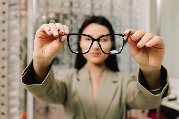 istock Customer chooses eyeglasses with clear lenses from the shelf. Eyesight correction. Stand of eyeglasses with different frames in the optical store. 2204008040