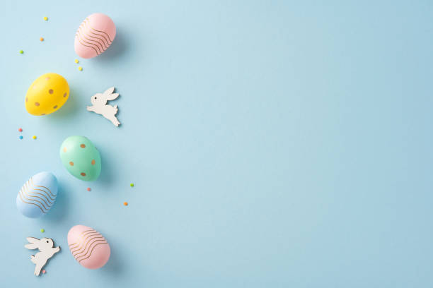 istock Colorful decorated Easter eggs and wooden bunny figurines artfully displayed on pastel blue 2204010880