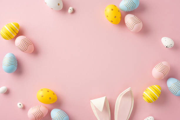 istock Easter-themed flat lay featuring colorful painted eggs with bunny ears on pink background 2204010887