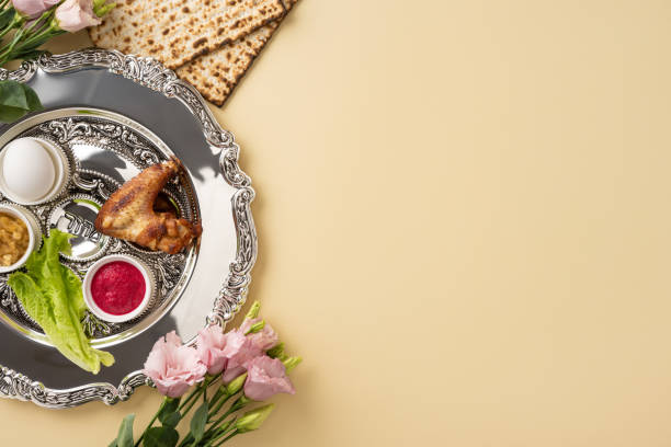 istock Celebrate Passover with a silver Seder plate featuring traditional foods and unleavened matzos, accompanied by decorative flowers on a beige background 2204010900