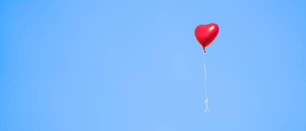 istock Heart shaped balloon rising into the sky 2204010972