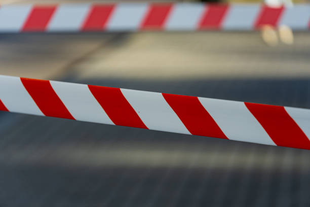 istock Bright red and white caution tape signals a restricted area at a community event, with blurred figures in the background enjoying the festivities 2204016131