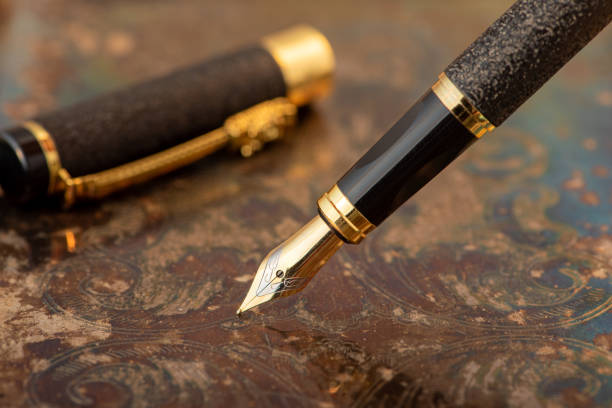 istock Fountain pen, beautiful fountain pen on an old metal surface with beautiful embossed ornaments, selective focus. 2204017721