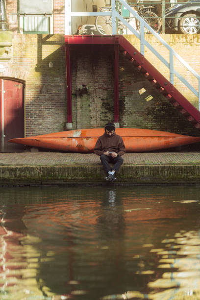 istock Young man using smartphone by canal in amsterdam 2204020183