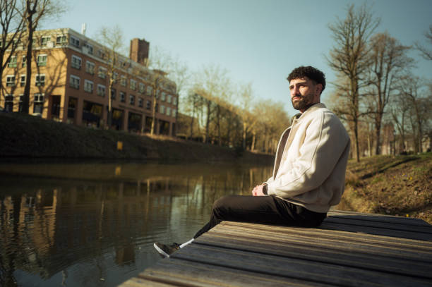 istock Young man with prosthetic leg sitting on pier looking away 2204020564
