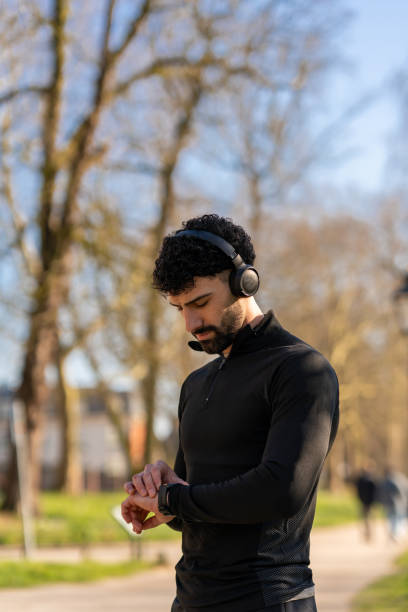istock Young sportsman checking performance on smartwatch during training in the park 2204020621