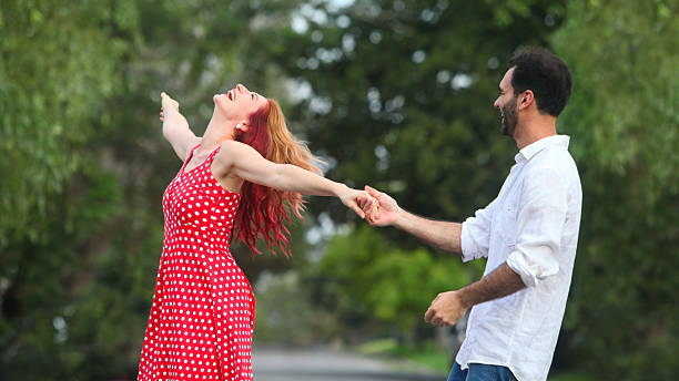 cheerful young man and woman dancing in park