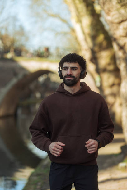 Young man jogging outdoors by the river wearing headphones