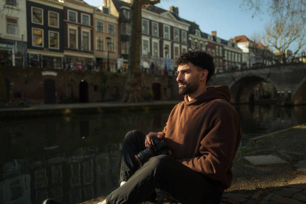 istock Photographer sitting by utrecht canal taking a break 2204022203