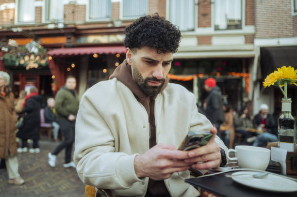 istock Young man using his phone in a cafe in amsterdam 2204022297