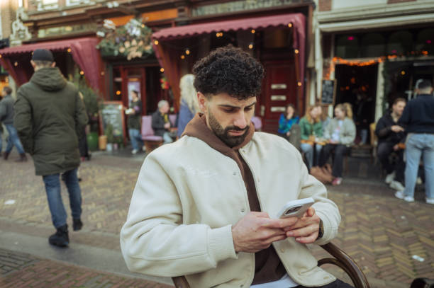 istock Young man using smartphone while sitting outside cafe in amsterdam 2204022299