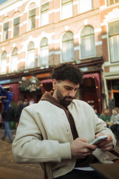 Young stylish man using phone in city center